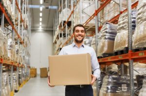 happy man with cardboard parcel box at warehouse